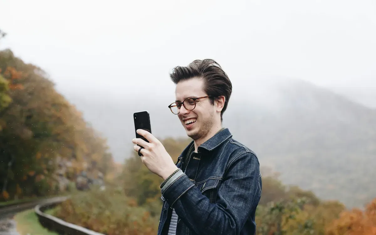 Mann lacht draußen beim Blick auf sein Smartphone