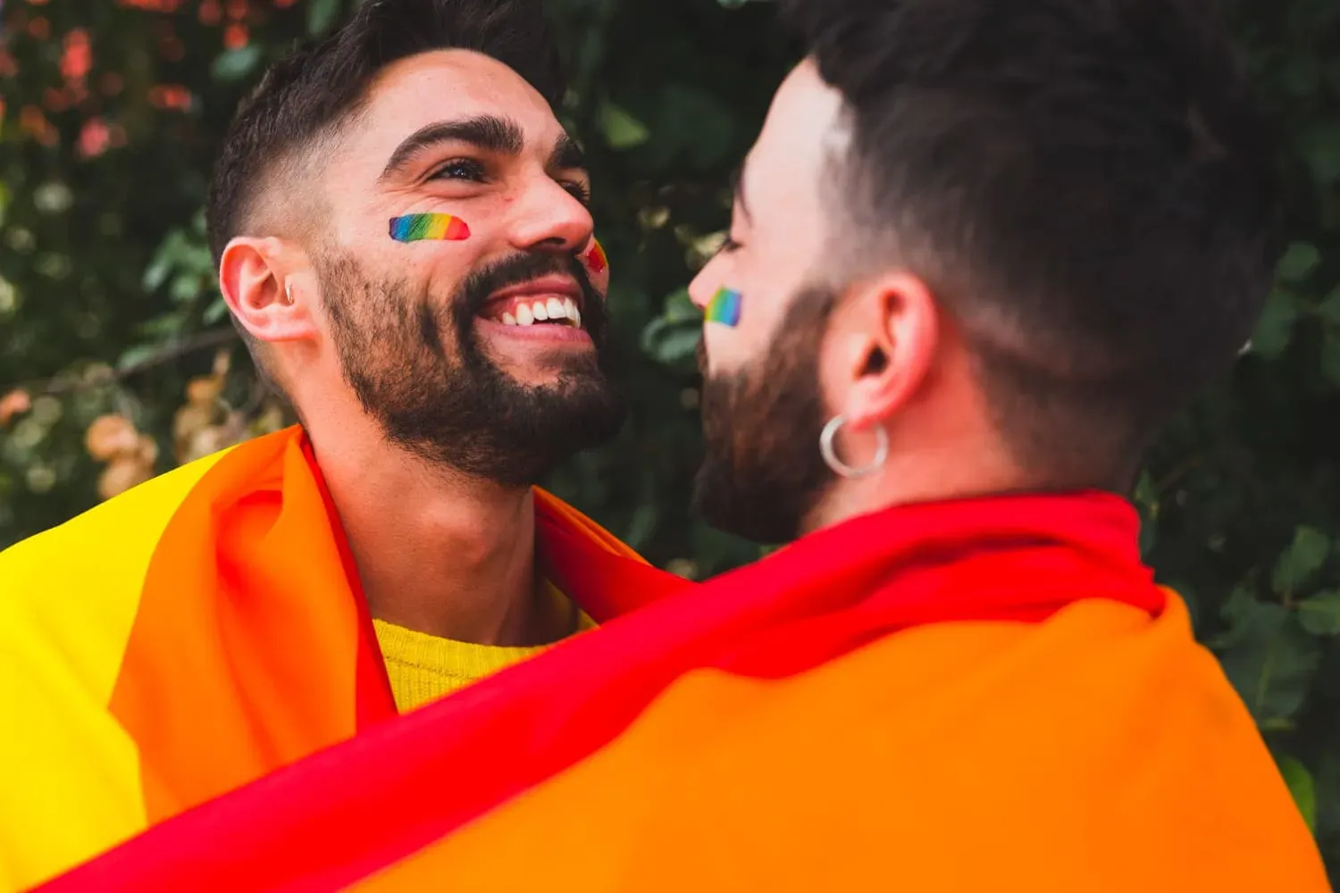 Zwei lachende Männer mit Regenbogenflagge – erstes Gay-Date