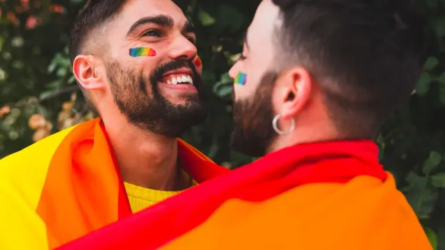 Zwei lachende Männer mit Regenbogenflagge – erstes Gay-Date