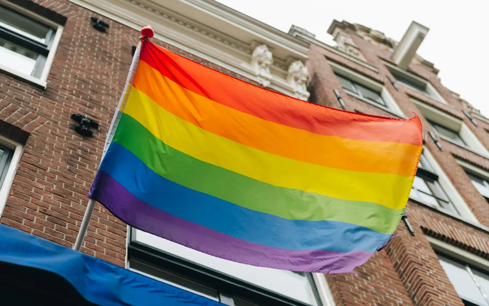 Regenbogenflagge weht vor einer Backsteinfassade in Amsterdam
